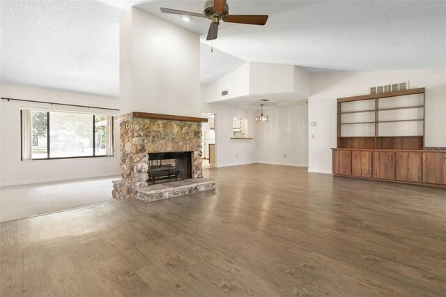 unfurnished living room with ceiling fan, high vaulted ceiling, dark carpet, a textured ceiling, and a stone fireplace