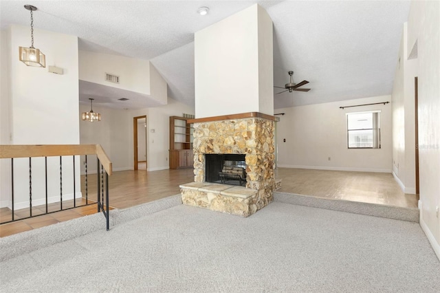 carpeted living room featuring a stone fireplace, ceiling fan with notable chandelier, and high vaulted ceiling