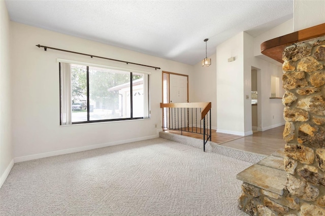 carpeted empty room with a textured ceiling and lofted ceiling