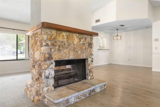 carpeted living room featuring a stone fireplace, high vaulted ceiling, and a textured ceiling