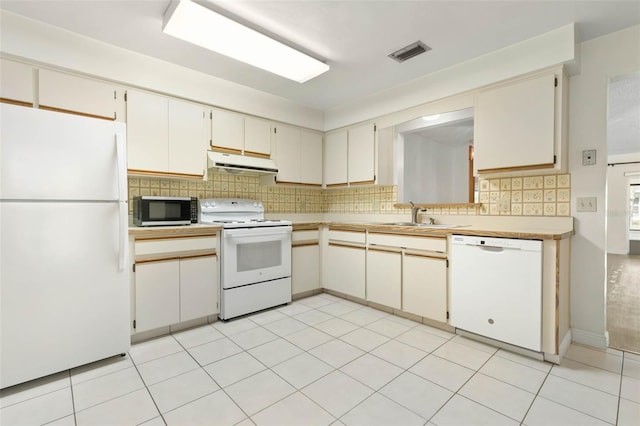 kitchen with decorative backsplash, white appliances, and light tile patterned floors