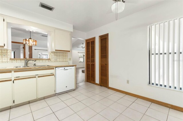 kitchen featuring tasteful backsplash, sink, light tile patterned floors, ceiling fan with notable chandelier, and dishwasher