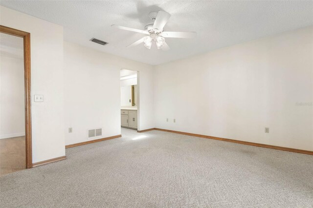 empty room featuring light carpet, ceiling fan, and a textured ceiling