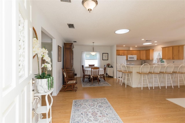 foyer entrance with light wood-type flooring and a textured ceiling