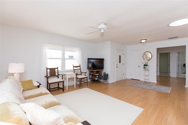 living room featuring light hardwood / wood-style floors, a textured ceiling, and ceiling fan