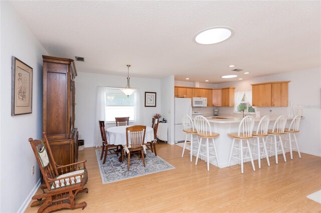 dining room with light hardwood / wood-style floors and a textured ceiling