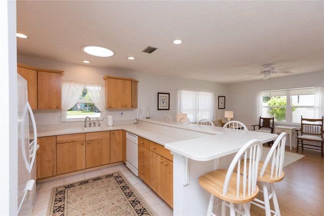 kitchen featuring a breakfast bar area, a wealth of natural light, kitchen peninsula, and ceiling fan