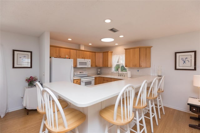 kitchen featuring light hardwood / wood-style floors, white appliances, and kitchen peninsula