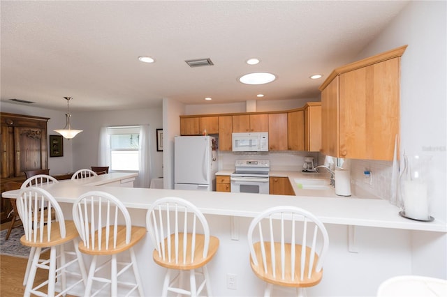 kitchen featuring tasteful backsplash, light wood-type flooring, white appliances, sink, and kitchen peninsula