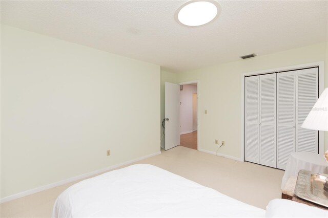 carpeted bedroom featuring a closet and a textured ceiling