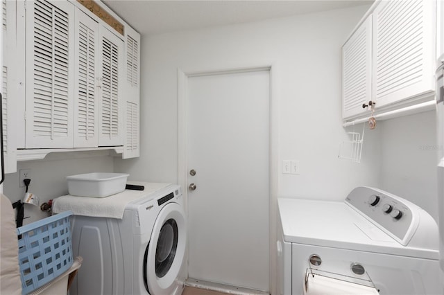 clothes washing area with cabinets and washer and dryer