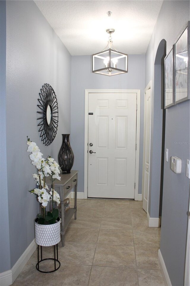 entryway with light tile patterned floors and an inviting chandelier