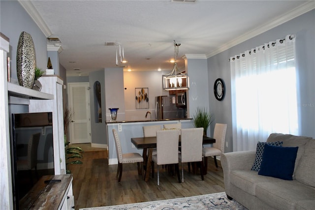 dining area featuring sink, ornamental molding, and hardwood / wood-style floors