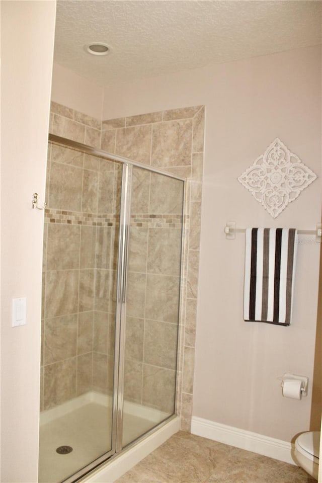 bathroom featuring tile patterned flooring, a textured ceiling, toilet, and an enclosed shower