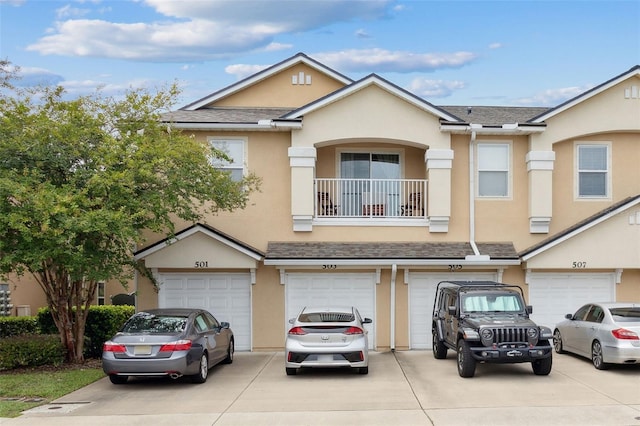 view of property featuring driveway, a balcony, an attached garage, and stucco siding