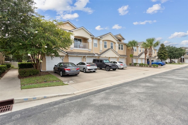 view of property with a garage, a residential view, driveway, and stucco siding