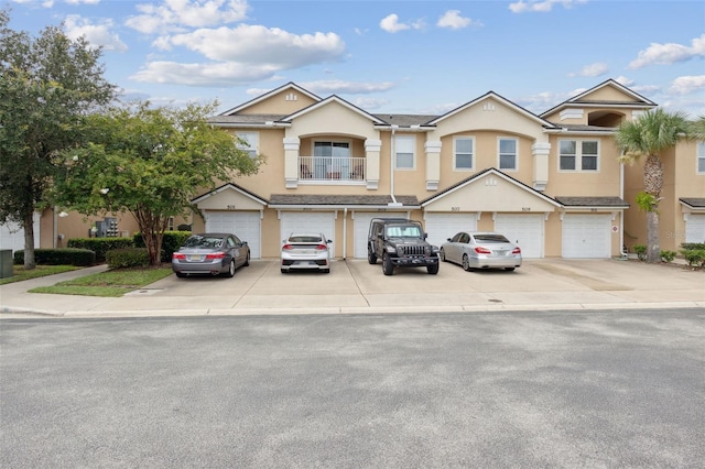 multi unit property with driveway, a balcony, an attached garage, and stucco siding