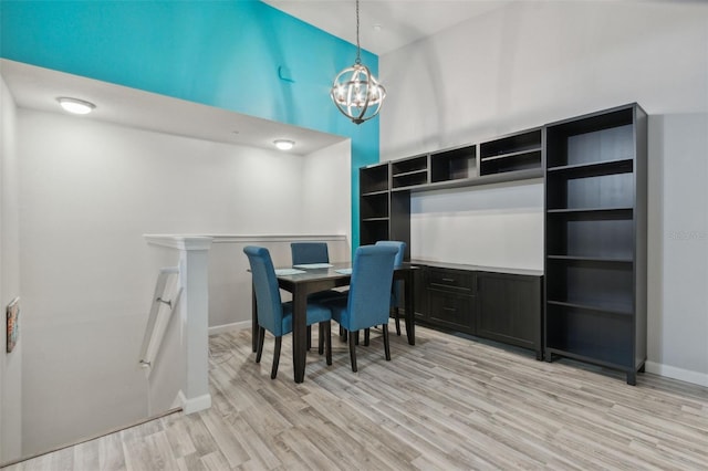 dining room featuring a notable chandelier, a high ceiling, baseboards, and light wood-style floors