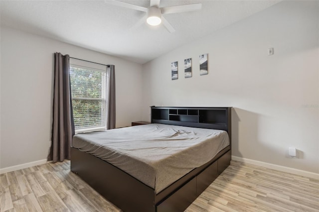 bedroom featuring a textured ceiling, a ceiling fan, light wood-style flooring, and baseboards