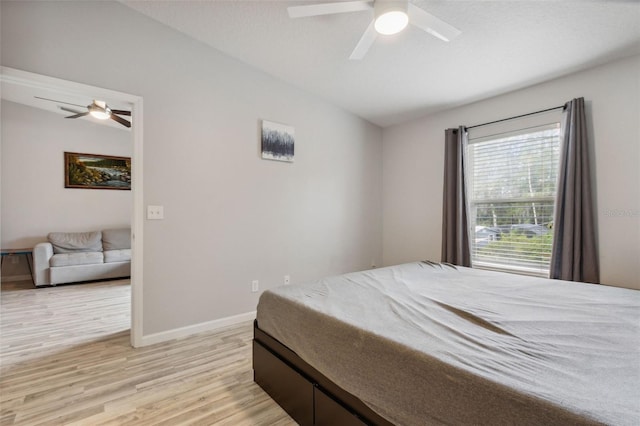 bedroom with lofted ceiling, light wood-style flooring, baseboards, and a ceiling fan