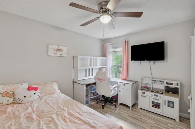 bedroom with ceiling fan, light wood-style flooring, and a textured ceiling