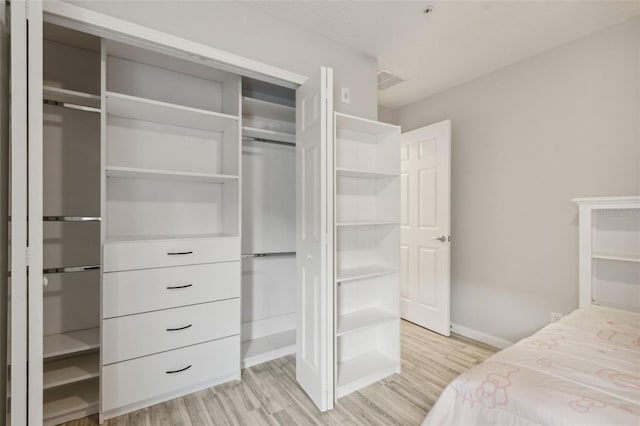 bedroom featuring light wood-style floors, baseboards, visible vents, and a closet