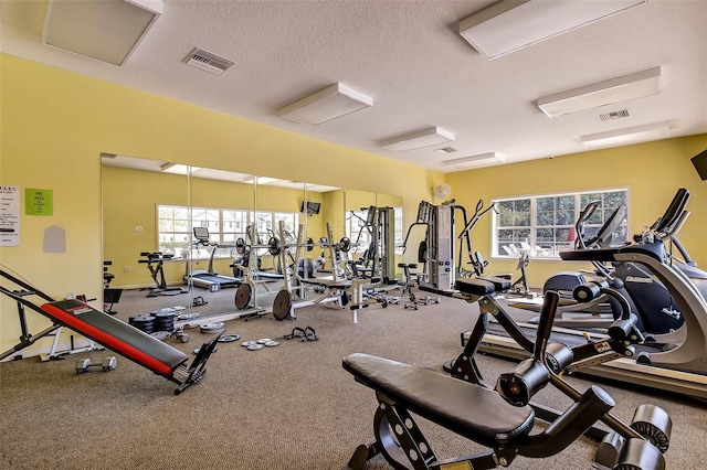 gym with attic access, visible vents, and a textured ceiling