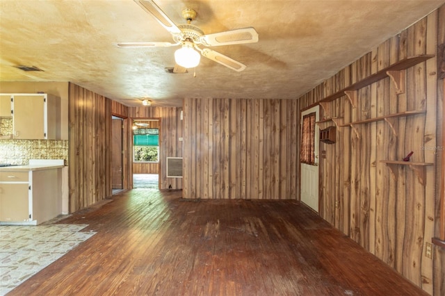 interior space with hardwood / wood-style flooring, wooden walls, and ceiling fan