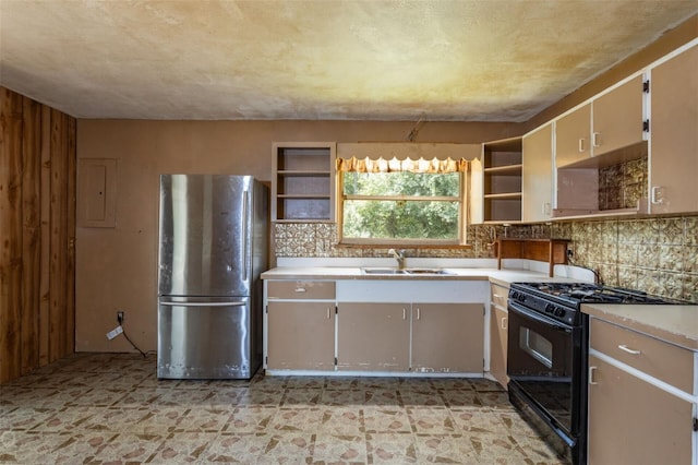 kitchen featuring black gas stove, sink, stainless steel refrigerator, and backsplash