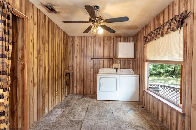 clothes washing area featuring ceiling fan, wooden walls, light carpet, cabinets, and washing machine and clothes dryer