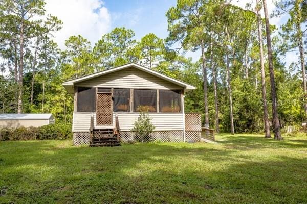 back of house featuring a sunroom and a lawn