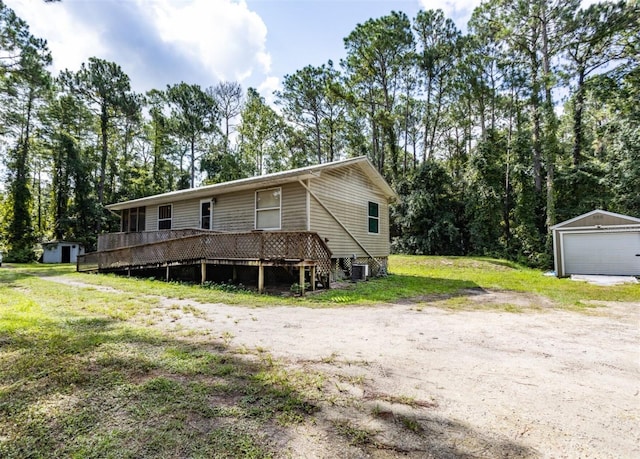 exterior space with a front lawn, a garage, a deck, central AC unit, and an outdoor structure