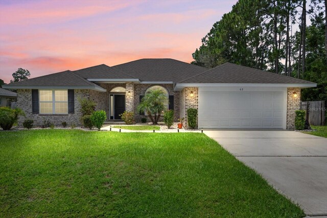 single story home with a garage and a lawn