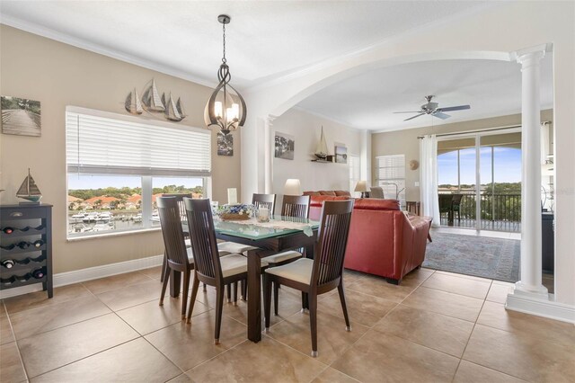 tiled dining space with decorative columns, ceiling fan with notable chandelier, and crown molding