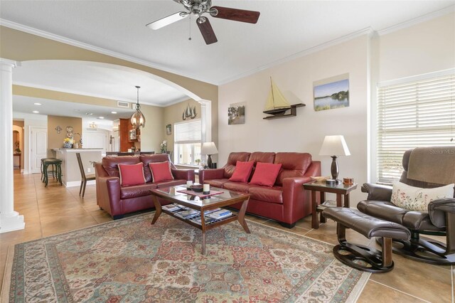 tiled living room with ceiling fan, decorative columns, and crown molding