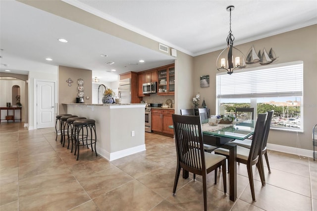 tiled dining room with an inviting chandelier and crown molding