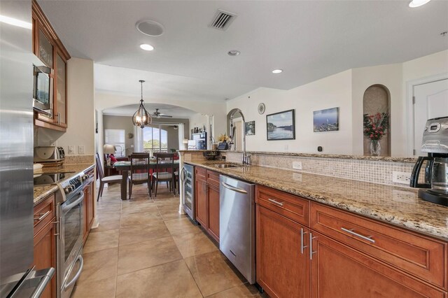 kitchen featuring stainless steel appliances, hanging light fixtures, decorative backsplash, ceiling fan, and light tile patterned flooring