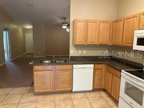 kitchen featuring sink, light tile patterned floors, white appliances, and kitchen peninsula