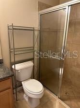 bathroom featuring vanity, toilet, an enclosed shower, and tile patterned flooring