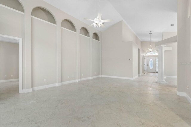 unfurnished room featuring ceiling fan, a high ceiling, and decorative columns