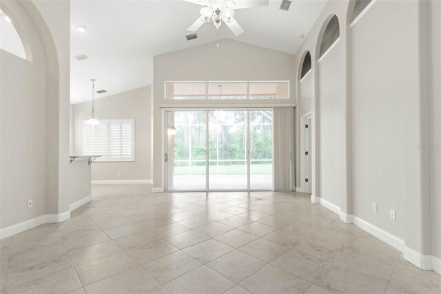 unfurnished room featuring ceiling fan, a wealth of natural light, vaulted ceiling, and light tile patterned flooring