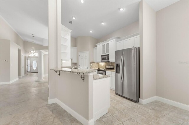 kitchen featuring light tile patterned flooring, appliances with stainless steel finishes, light stone countertops, white cabinets, and kitchen peninsula