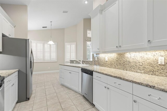 kitchen with dishwasher, white cabinetry, light stone counters, and vaulted ceiling