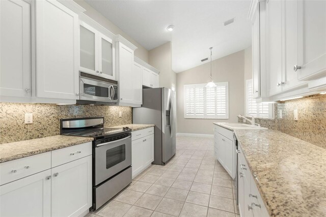 kitchen with lofted ceiling, decorative backsplash, light tile patterned floors, white cabinetry, and appliances with stainless steel finishes