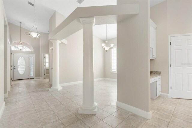 tiled entryway featuring a high ceiling, ornate columns, and a notable chandelier