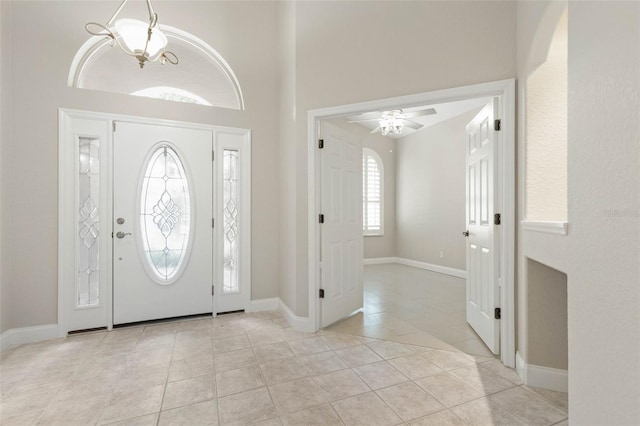 tiled foyer with ceiling fan and a towering ceiling