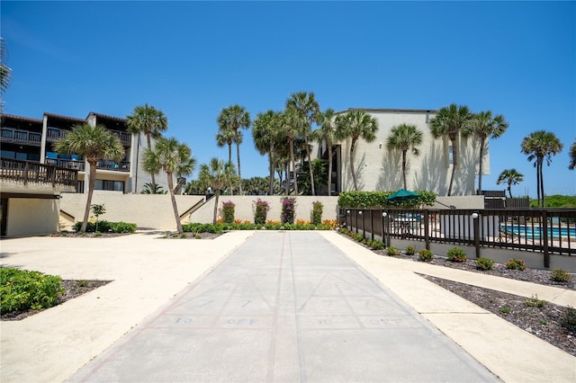 view of home's community with fence, a pool, and a patio