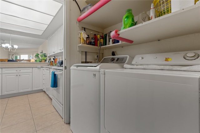 clothes washing area with light tile patterned floors, a chandelier, and washing machine and clothes dryer