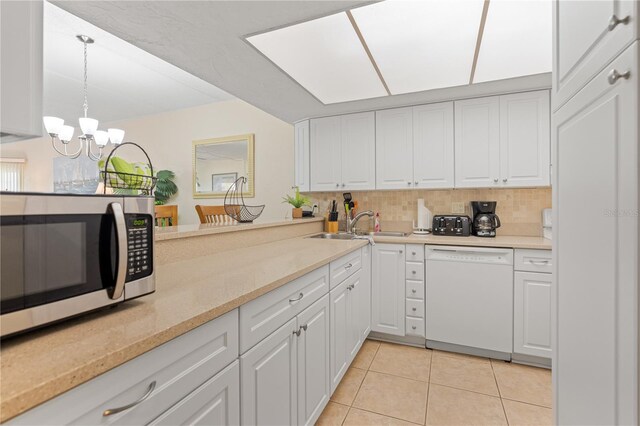 kitchen with white cabinetry, dishwasher, decorative light fixtures, and a notable chandelier