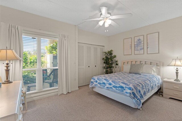 carpeted bedroom with ceiling fan and a closet